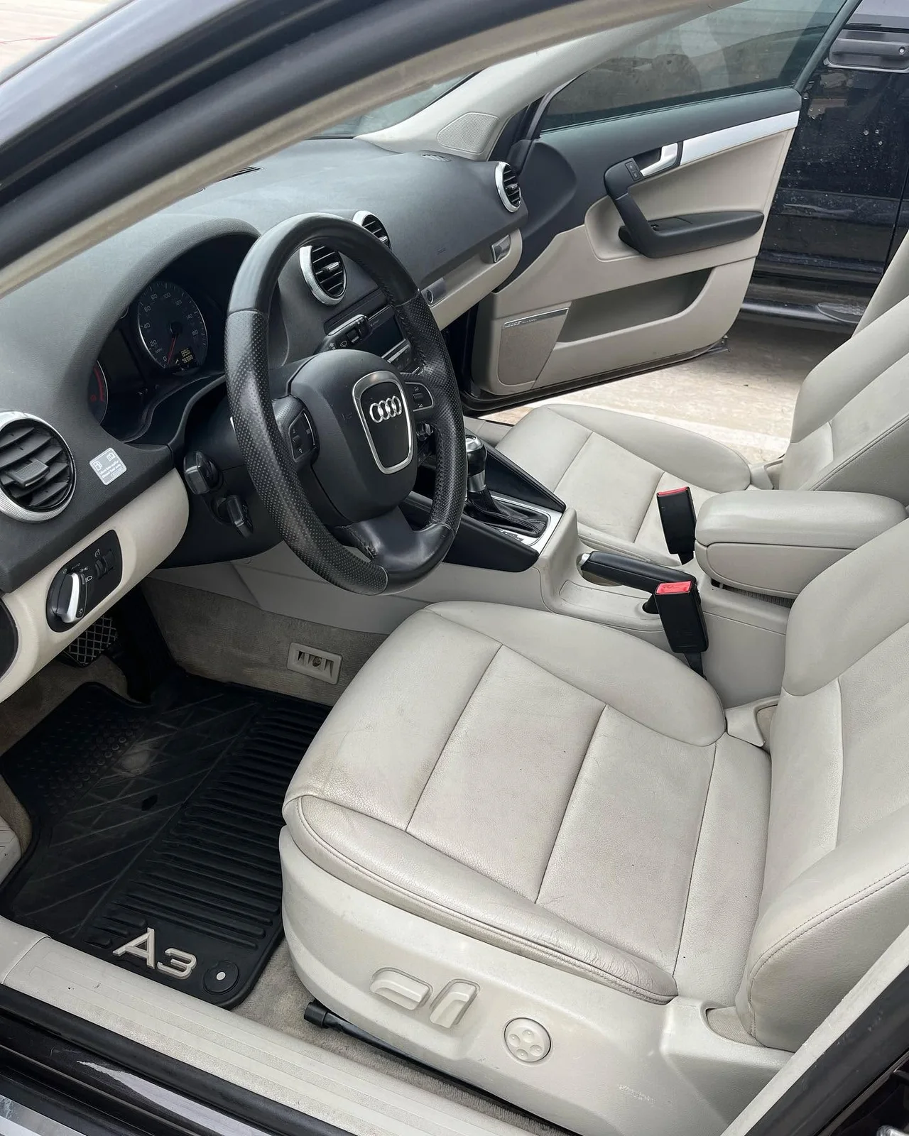 Clean light leather Audi interior viewed through the open driver door