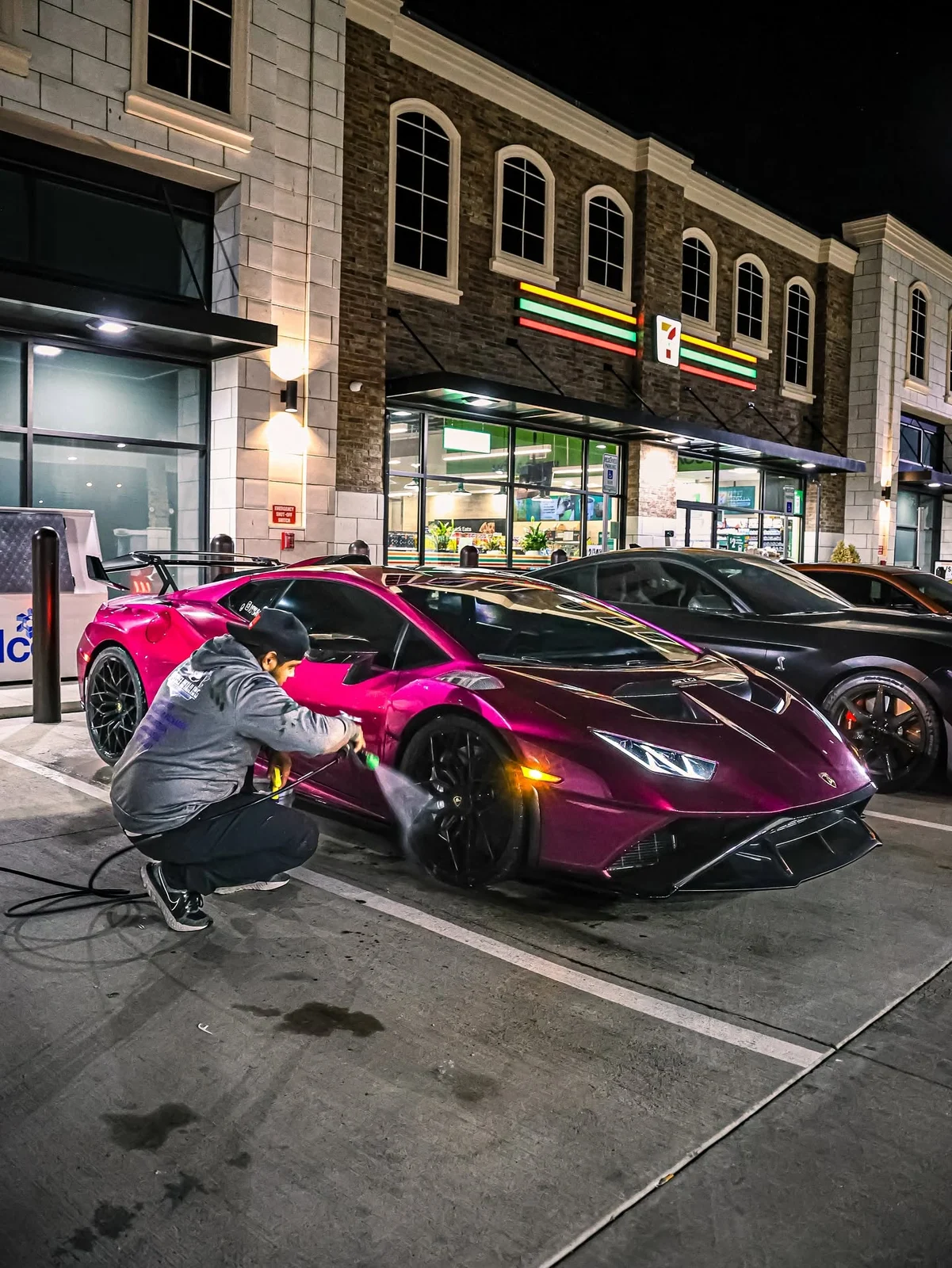 David working beside a magenta Lamborghini at night