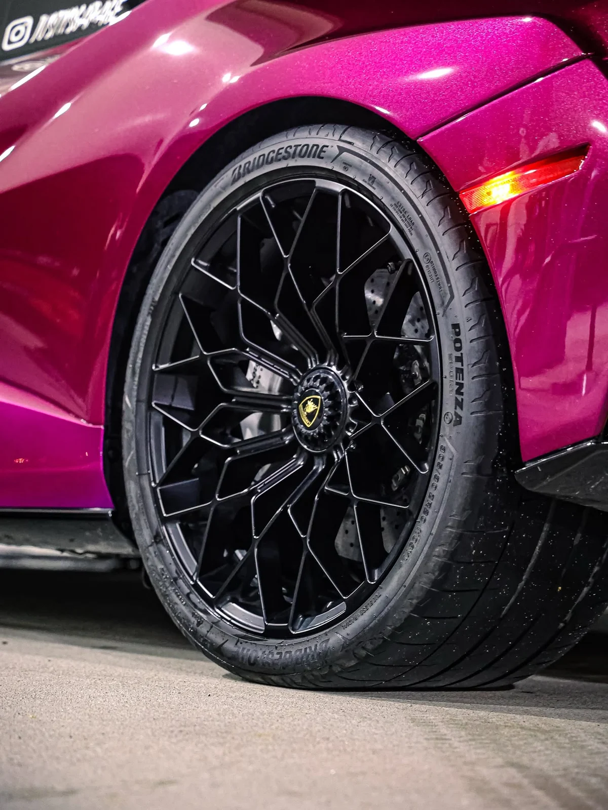 Freshly finished black Lamborghini wheel against metallic magenta paint